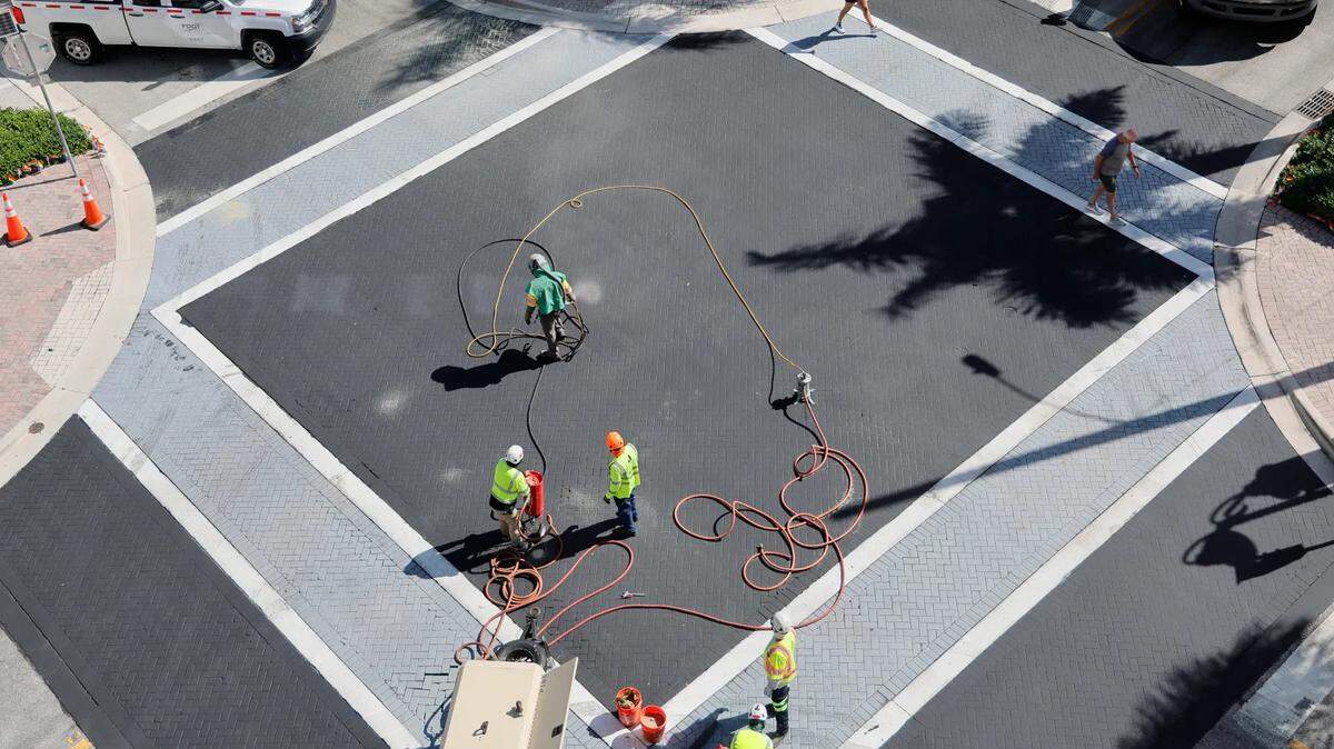 People cross the street Wednesday, Sept. 10, 2025, as workers wrap up the removal of a rainbow-colored pride display at Northeast First Street and Northeast Second Avenue in Delray Beach.