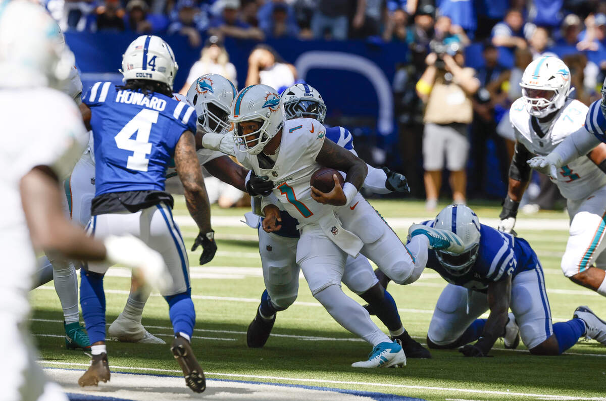 Miami Dolphins quarterback Tua Tagovailoa (1) is chased by Indianapolis players during the first half of an NFL game at Lucas Oil Stadium on Sunday, Sept. 7, 2025, in Indianapolis.