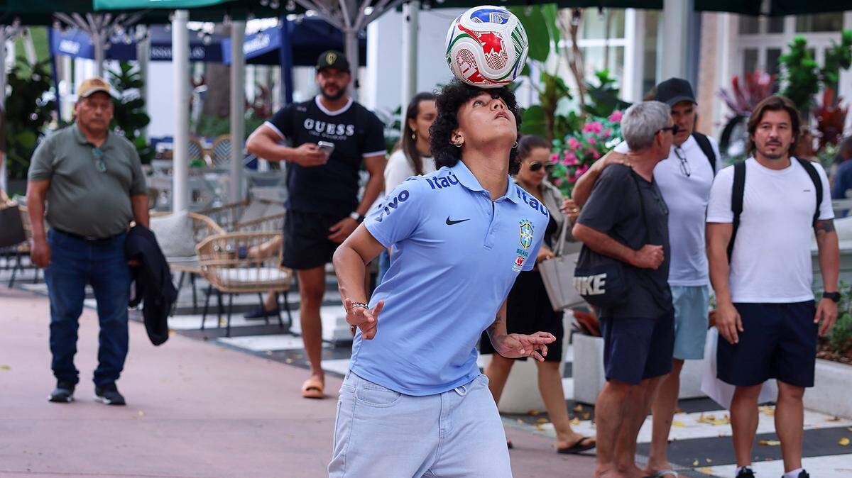 St. Thomas University soccer players, Ricky Martinez, 22, balances a soccer ball on his head while he and others wait to enter the new FIFA World Cup store. Influencers and creators from Miami and around the world attended a private shopping experience during the grand opening of the official FIFA World Cup store on Lincoln Road Mall, Thursday, in Miami Beach, Florida.