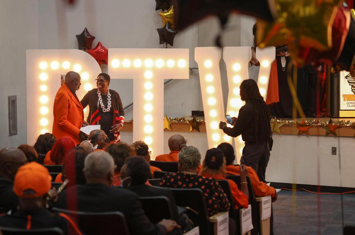 Yolanda Jackson, en el centro, pone su mano sobre su tío, George Storr, a la izquierda, miembro de la asociación de ex alumnos, antes de la ceremonia de entrega de premios a los estudiantes el martes 24 de mayo de 2022 en Miami en la escuela preparatoria Booker T. Washington. Los padres de Jackson estudiaron en la escuela preparatoria Booker T. Washington.