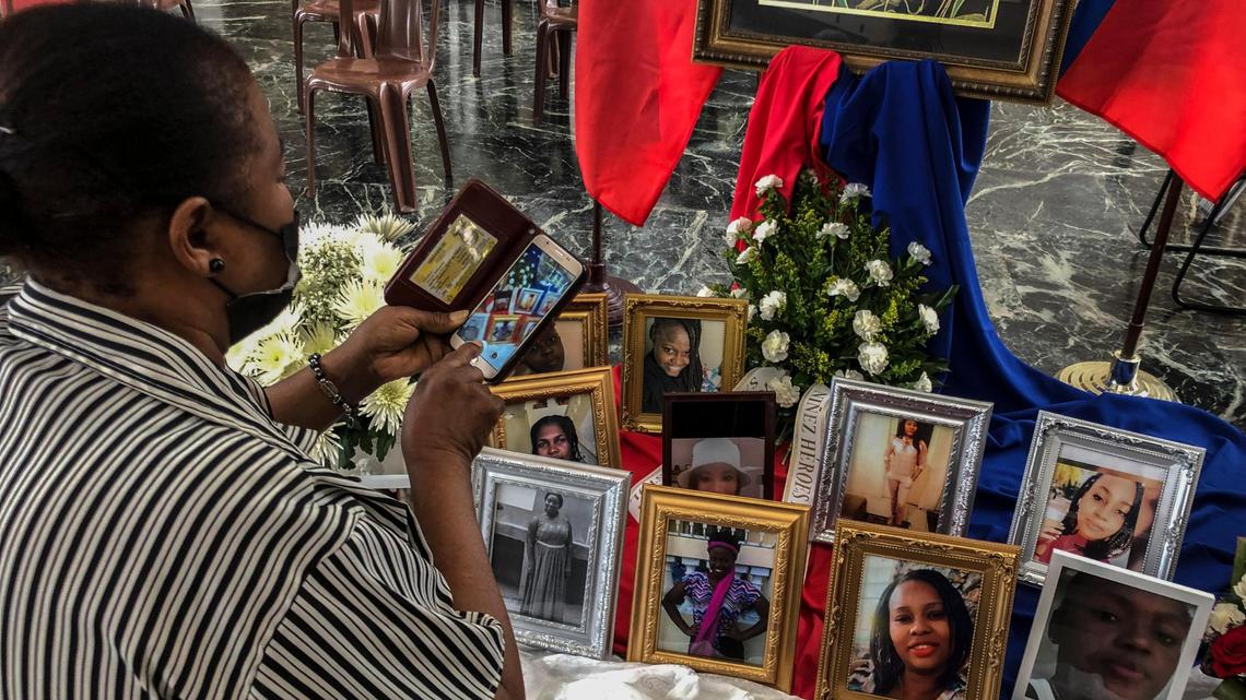 A woman takes a photo of the images of the 11 Haitian women who died last month when the overloaded boat they were in capsized, at a church in San Juan, Puerto Rico, Wednesday, June 15, 2022. The boat was carrying an estimated 60 to 75 migrants, of which eleven were found dead, at least a dozen still missing and 38 rescued.