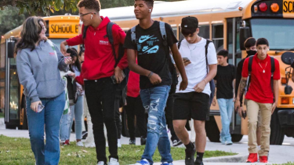 Estudiantes entran en el campus desde el circuito de autobuses el primer día de clase en la preparatoria Miami Beach, en Miami Beach, Florida, el 17 de agosto de 2022.