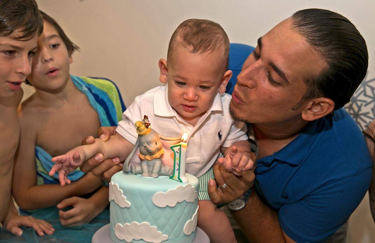 Sebastian de la Cruz observes his first birthday with family in Miami on Saturday, Sept. 20, 2014. Holding Sebastian is his father, Robinson de la Cruz. Sebastian is the child who stopped breathing while being driven by his aunt, Pamela Rauseo, on the Dolphin Expressway in February 2014.