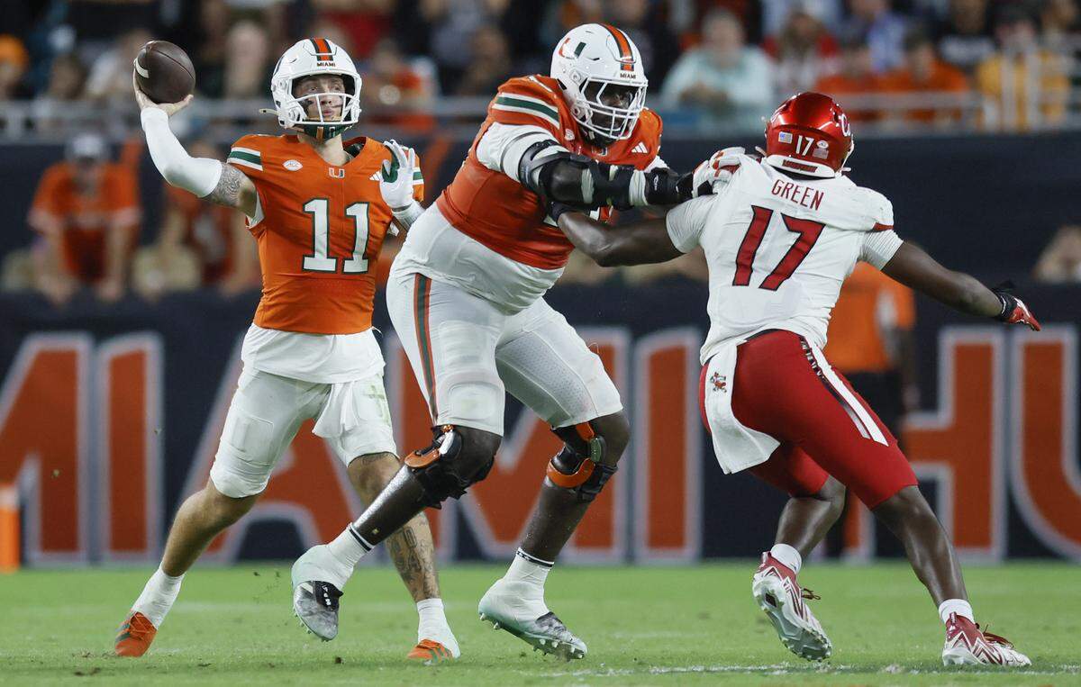 Miami Hurricanes quarterback Carson Beck (11) sets up to pass as offensive lineman Markel Bell (70) blocks Louisville Cardinals defensive lineman AJ Green (17) in the second half of their NCAA football game at Hard Rock Stadium in Miami Gardens, Florida, on Friday, October 17, 2025.