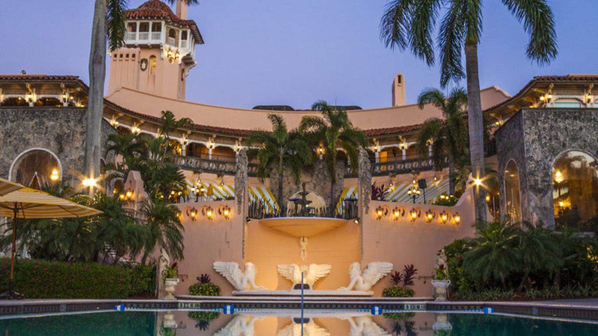 Lights and palm trees frame the outdoor dining patio, overlooking the parrot pool, at Mar-a-Lago.