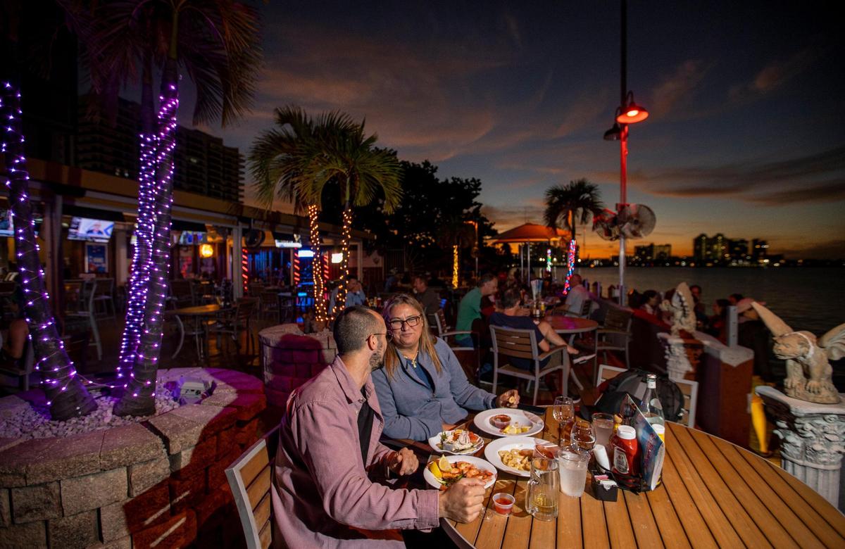 Ignacio Seijo, left, and Andrea liguori enjoy a meal at Shuckers Waterfront Bar & Grill on Tuesday, Nov. 15, 2022, in North Bay Village, Fla. Many North Bay Village residents raise concerns for the future of their community, fearing the wave of new projects will bring unwanted housing density and traffic congestion.