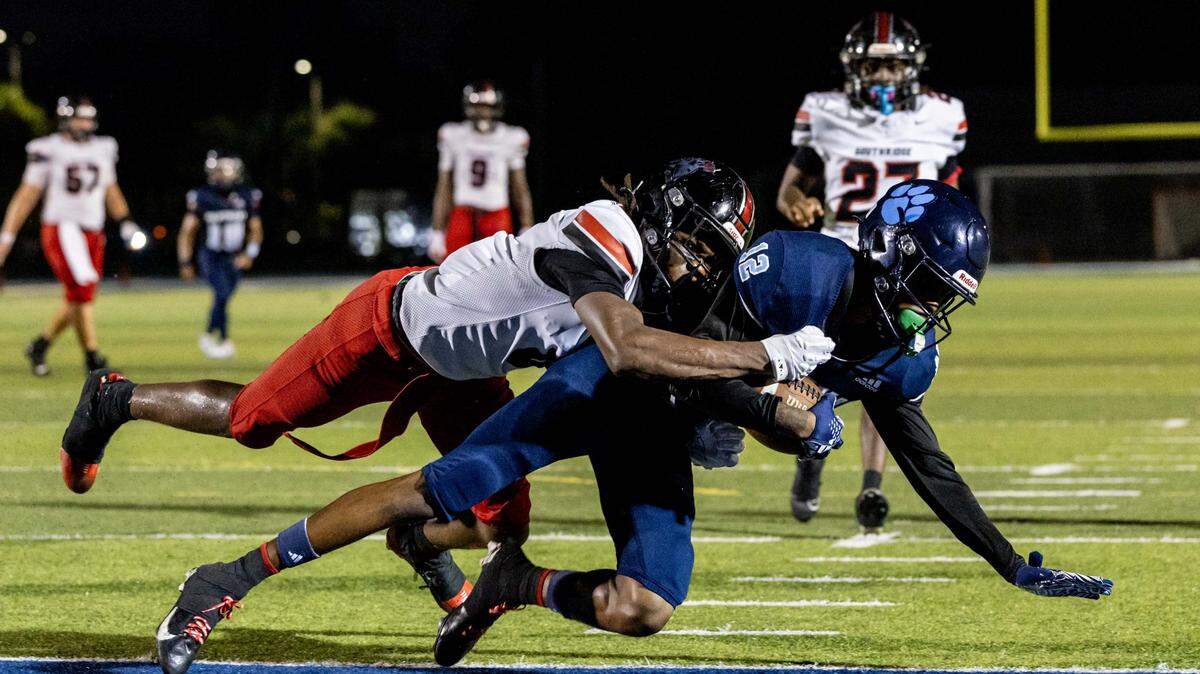 Panthers wide receiver Willie Wilson (12) gets tackled by Spartans defensive back Jean Calixte (8) as he scores a touch down during the second half of a high school football game between Palmetto and Miami Southridge at Tropical Park on Thursday, September 4, 2025, in Miami, Fla.