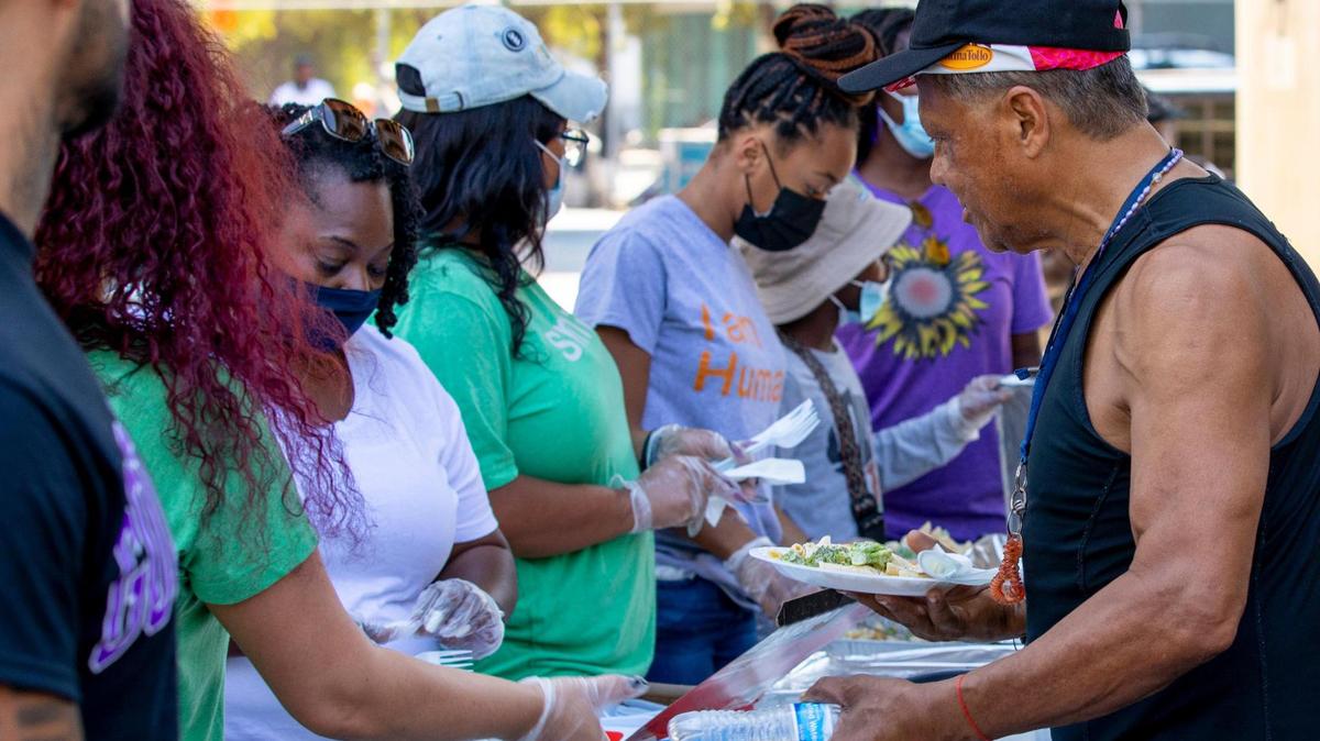 A homeless man gets some food during a donation and feeding event hosted by The Smile Trust, Inc. near Southwest 2nd Avenue and Second Street in Downtown Miami, Florida, on Sunday, October 17, 2021. The Smile Trust, Inc. is an International Nonprofit Organization that fights against homelessness and works toward fixing food insecurities.