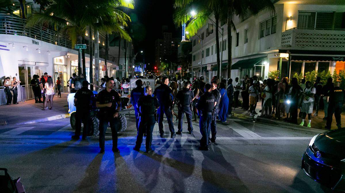 Un grupo de agentes de policía se reúne en Ocean Drive y la 8th Street en Miami Beach, Florida, el viernes 25 de marzo de 2022. Las autoridades de la ciudad impusieron un toque de queda a medianoche y obligaron a las tiendas a dejar de vender alcohol después de las 6 p.m. Las restricciones se establecieron después de que dos tiroteos en Miami Beach el fin de semana anterior hicieran que las autoridades de la ciudad anunciaran el "estado de emergencia".