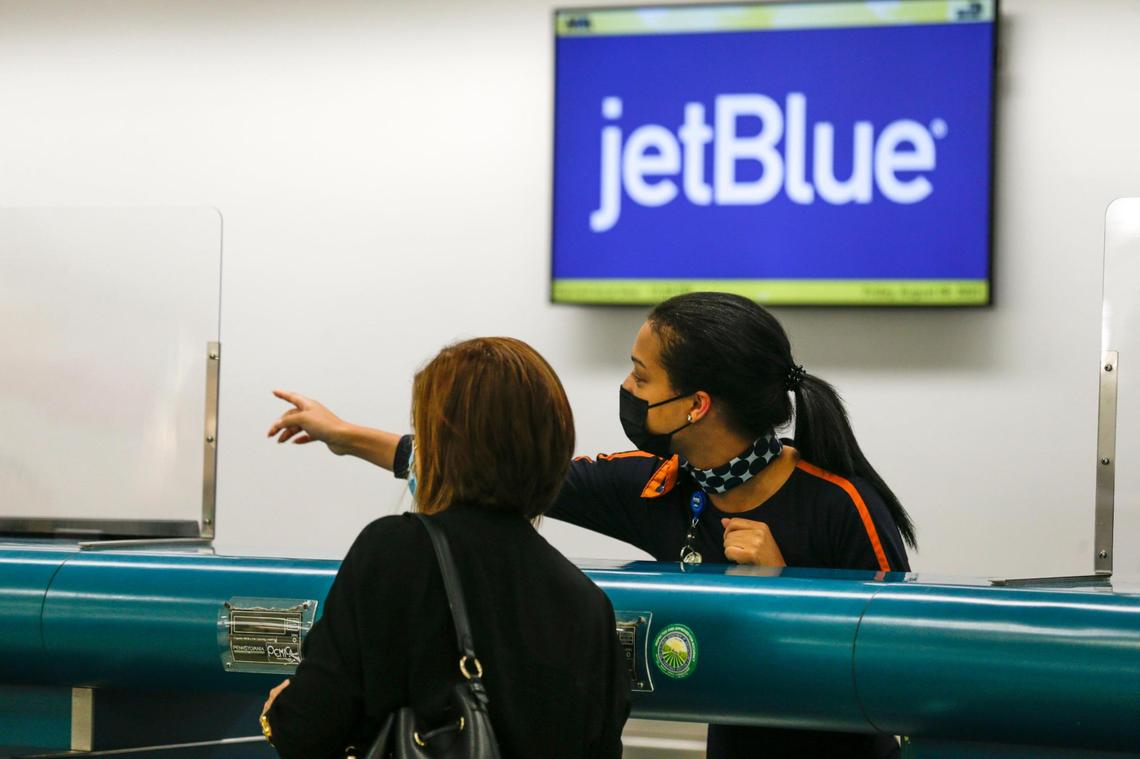 An employee at the JetBlue ticket counter shows the way to a traveler at Miami International Airport in Miami, on Aug. 6, 2021.