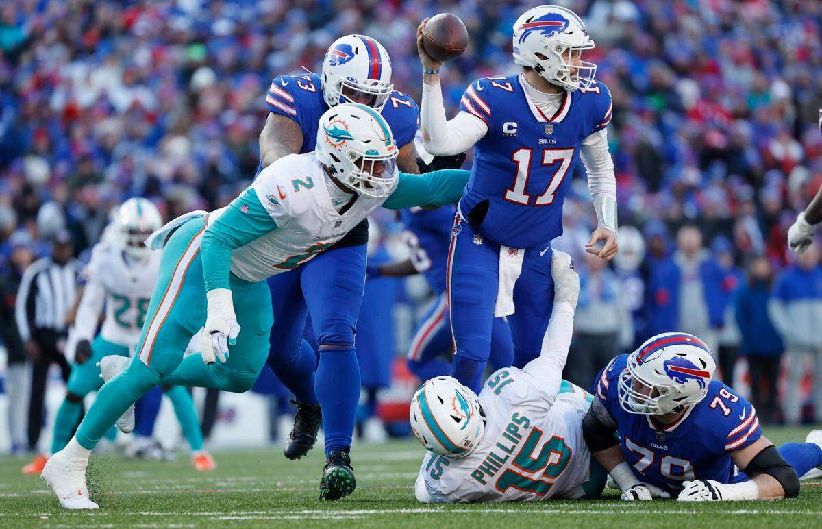 Buffalo Bills quarterback Josh Allen (17) completes a pass despite the pressure by Miami Dolphins linebacker Bradley Chubb (2) and linebacker Jaelan Phillips (15) in the third quarter of the NFL wild-card football game at Highmark Stadium, Orchard Park, NY, on Sunday, January 15, 2023.