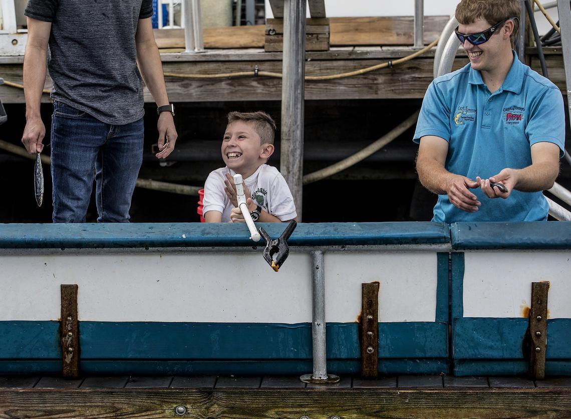 Joshua Lewis (right) , son of Captain Jimmy Lewis, helps 10 year-old Ian Duarte of Costa Rica feed a tarpon at Bayside marina.