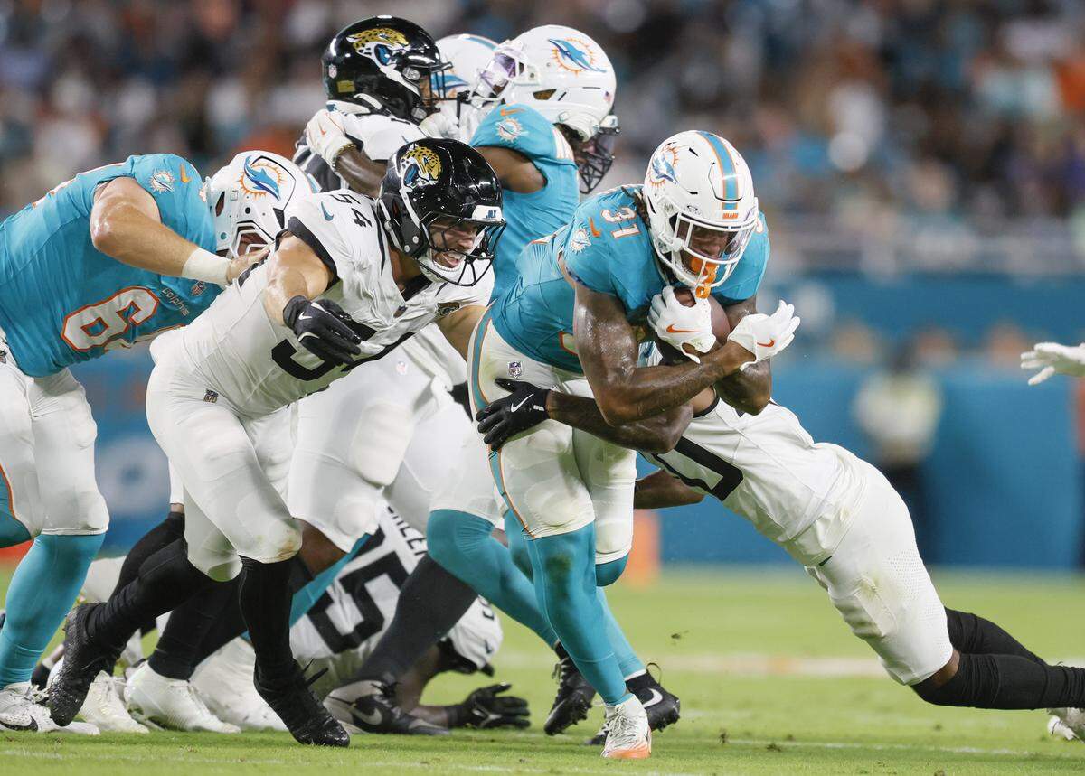 Miami Dolphins running back Ollie Gordon II (31) rushes for a first down against the Jacksonville Jaguars in the first half of an NFL football game at Hard Rock Stadium in Miami Gardens, Florida, on Saturday, August 23, 2025.