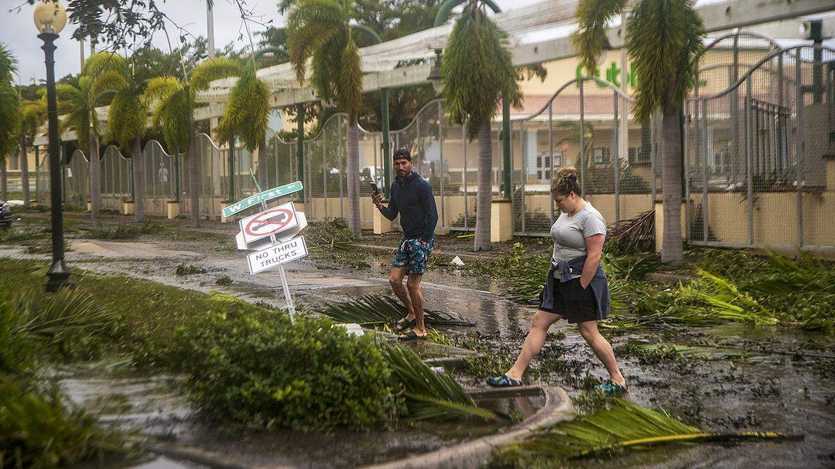 Annabel Chaetlur y Henry Comas atraviesan el barro dejado por la marea del río Caloosahatchee un día después que el huracán Ian azotara la costa oeste de la Florida como tormenta de categoría 4, el jueves 29 de septiembre de 2022