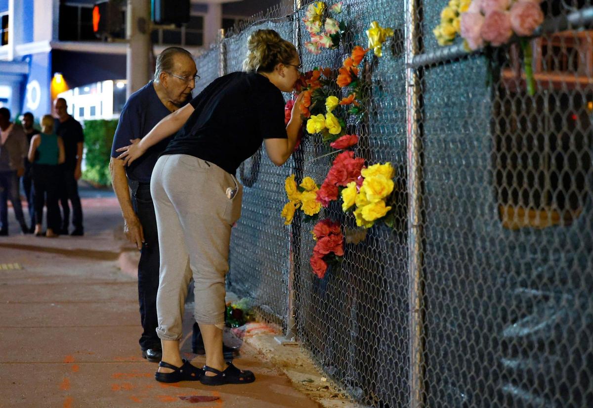 Deven Gonzalez, a survivor who escaped the collapse of Champlain Towers South, kisses a bouquet of flowers in honor of her father Edgar Gonzalez who died as she reaches out to her grandfather Jose Antonio Gonzalez on the two-year anniversary in Surfside, Florida on Saturday, June 24, 2023.
