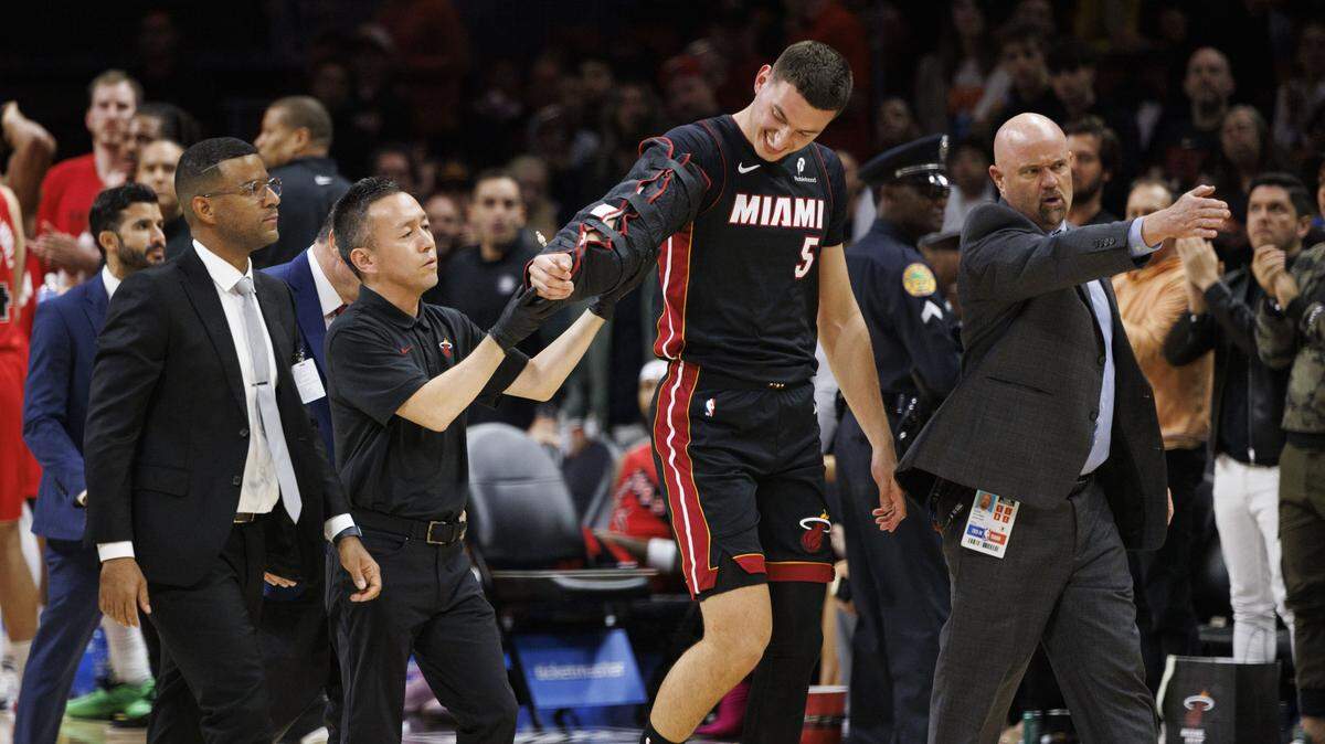 Miami Heat forward Nikola Jovic (5) is escorted off the court after getting fouled by Toronto Raptors forward Collin Murray-Boyles (12) and hurting his arm during the first half of a game on Dec. 15, 2025, at Kaseya Center inMiami.