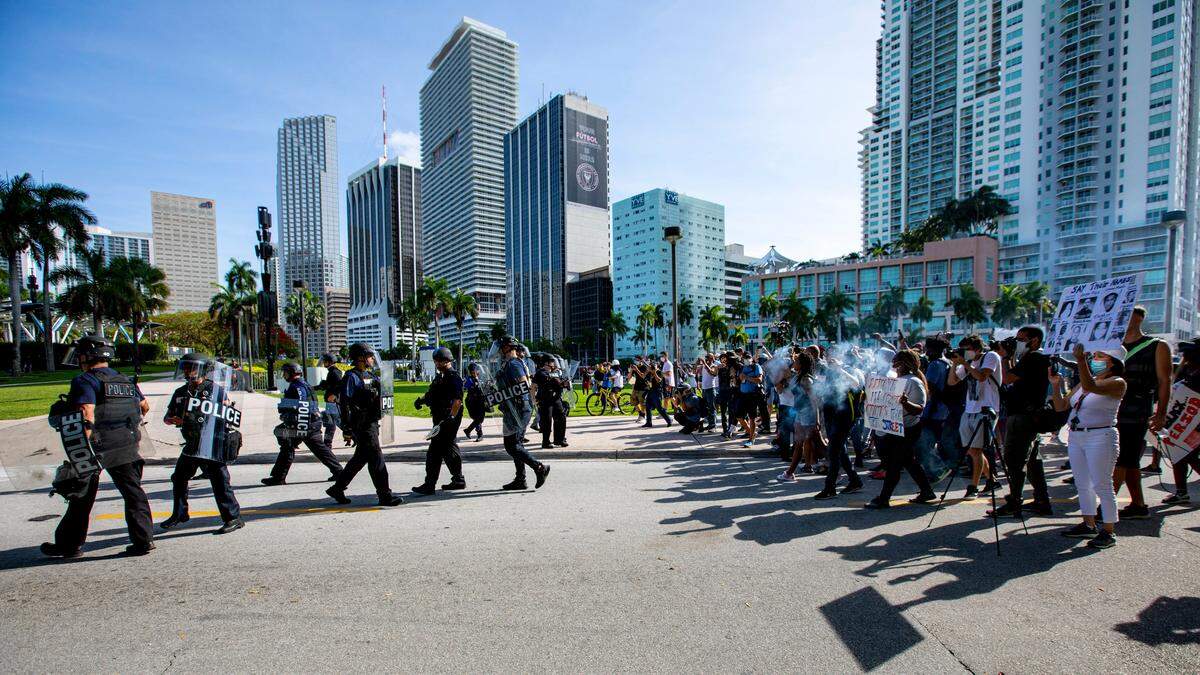 Officers walk away from demonstrators during a protest in downtown Miami.