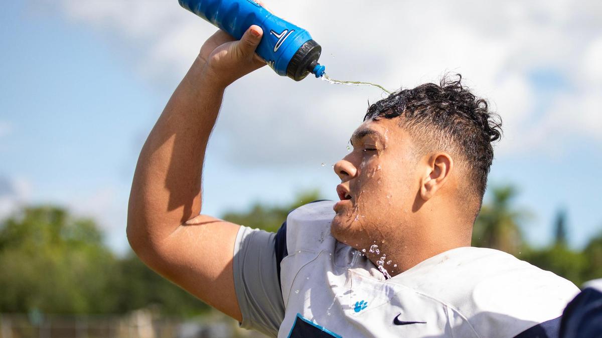 Johnny Mejia, offensive lineman, pours water on his head to cool down during the Palmetto Panthers football practice on Monday, Aug. 7, 2023 in Pinecrest, Fla.