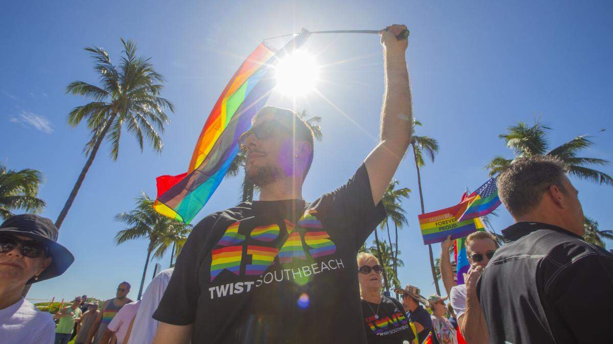 Jansen Perry waves a flag alongside demonstrators carrying rainbow flags and signs reading ‘Miami Beach Forever Proud’ and ‘Won’t Be Erased’ during the Forever Proud March on Ocean Drive in Miami Beach, Fla., Sunday, Aug. 31, 2025, held after state officials ordered the removal of the city’s LGBTQ Pride crosswalk.