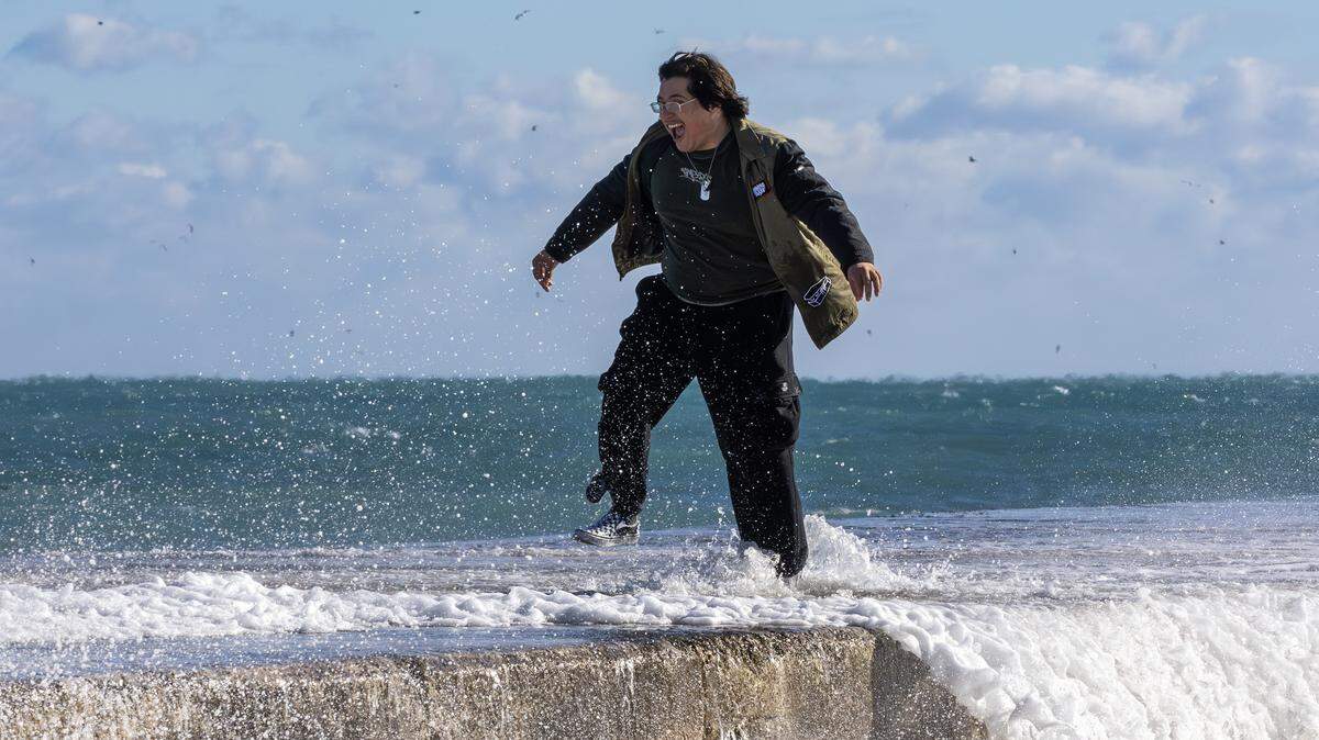 Ryan Romero of Naples, Fla., reacts as waves crash against the jetty near the Bal Harbour Lighthouse on Sunday, Feb. 1, 2026, in Bal Harbour, Fla. It was a cool day that day. But except temperatures around 80 and about a 20% rain chance for the Passover and Easter holidays on April 1 through 5, 2026.