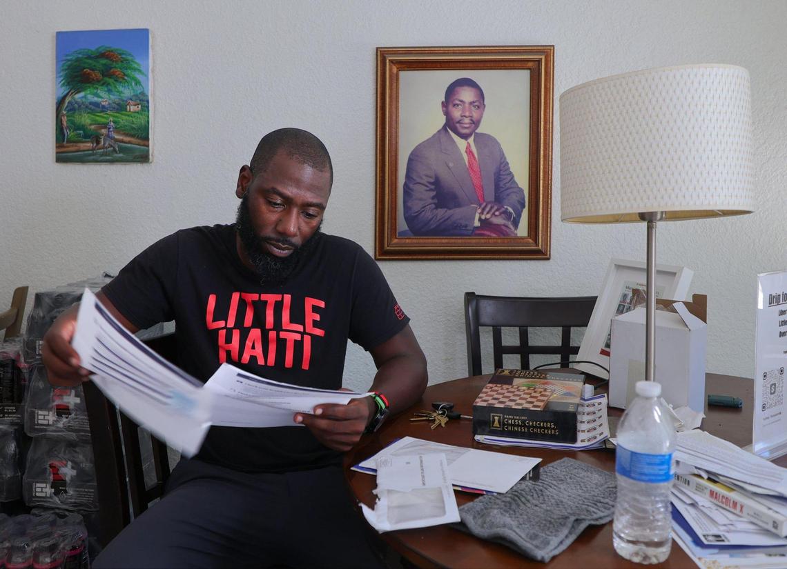 Little Haiti resident Ashley Toussaint checks his mail while a photo of his father, Ellison Toussaint, is displayed on the wall. Ashley rescued his father’s home after moving back to Miami from Brooklyn, NY. Toussaint says he received multiple requests to sell but refused offers while transforming the property into his home.