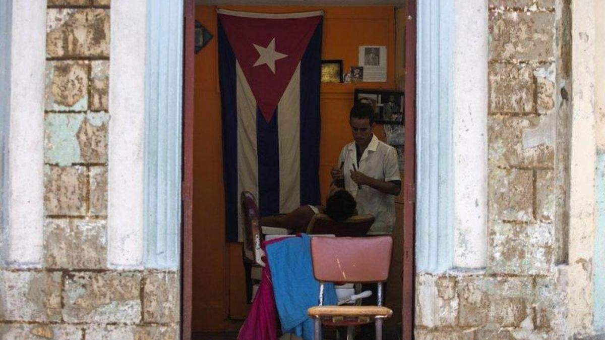 A Cuban barber shaves a customer at his privately owned shop in Havana.
