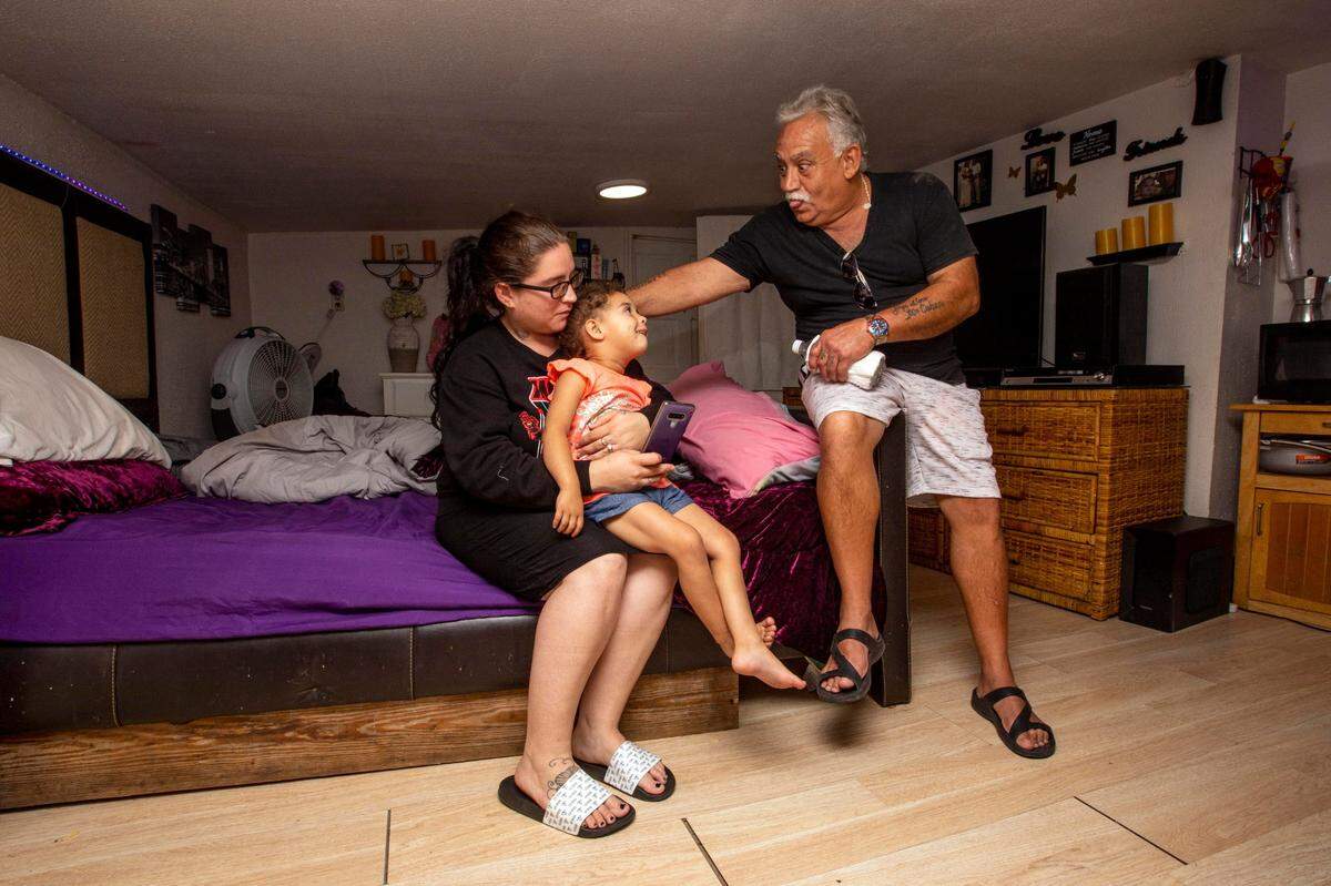 Mobile home park resident and mother Brandy Sarut, 24, looks on as her father, George Sarut, plays with his granddaughter, Mariana, inside their home as the family faces a possible eviction from a non-subsidized affordable housing park by developers near the Miami River in Miami, Florida, on Tuesday, June 1, 2021.