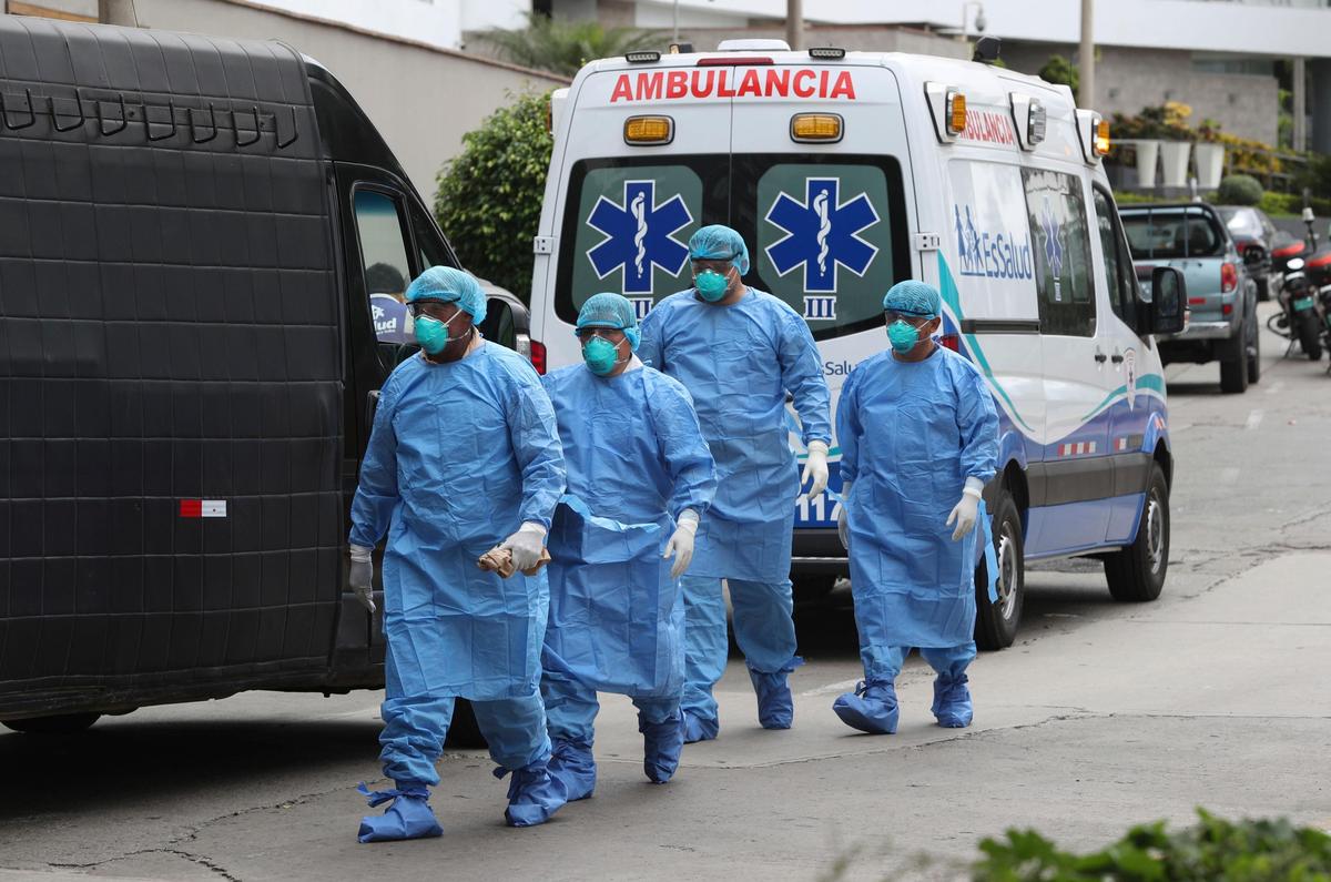 Health workers arrive at an apartment building to remove the body of a person who died of the new coronavirus in Lima, Peru, Friday, March 20, 2020. Peru is in its fourth day of a state of emergency, decreed by the government, amid the new coronavirus outbreak.