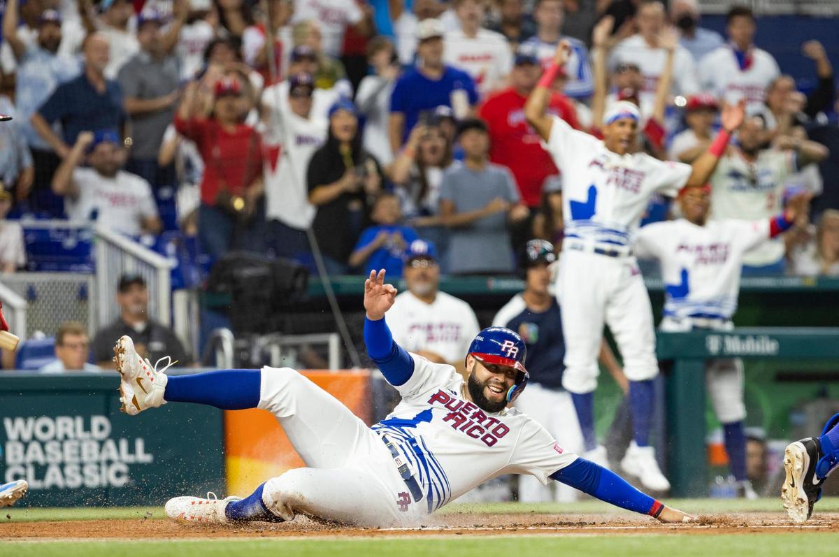 Puerto Rico third baseman Emmanuel Rivera (26) slides into home plate after Puerto Rico second baseman Javier Baez (9) doubles on a sharp line drive to left field against Israel during the first inning of a Pool D game at the World Baseball Classic at loanDepot Park on Monday, March 13, 2023, in Miami, Fla.