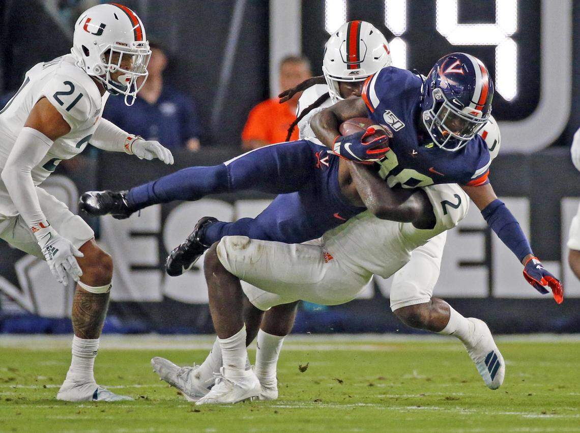 Miami Hurricanes defensive back Trajan Bandy (2) upends Virginia Cavaliers wide receiver Tavares Kelly Jr. (88) in the first quarter as the University of Miami host the Virginia Cavaliers at Hard Rock Stadium in Miami Gardens on Friday, October 11, 2019.