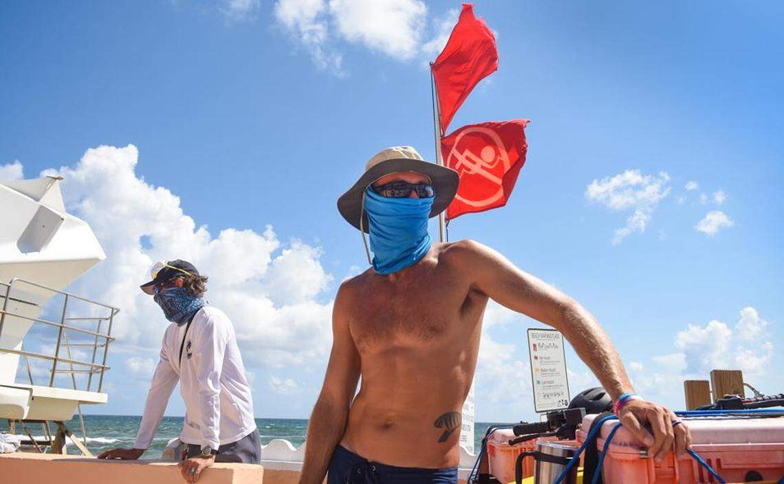 Palm Beach lifeguards Ryan Zabovnik, left, and George Klein wear masks at Midtown Beach in Palm Beach after red tide appeared on Palm Beach County last month.