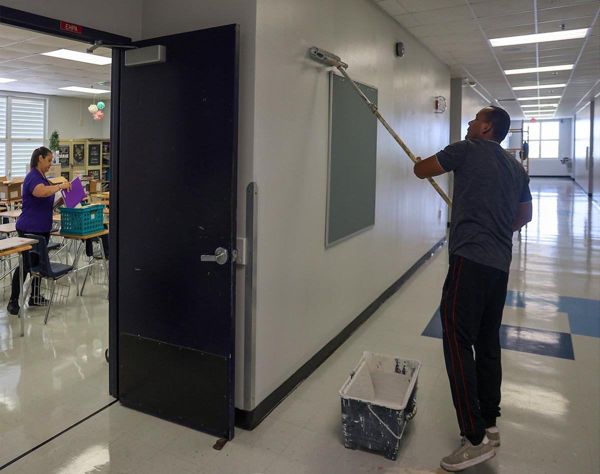 A maintenance workers add a fresh coat of paint to the hallway wall at Southwest Miami Senior High School. Miami-Dade, the largest landowner in the county, is struggling to maintain building facilities as state law forces them to share additional funds with charter schools.
