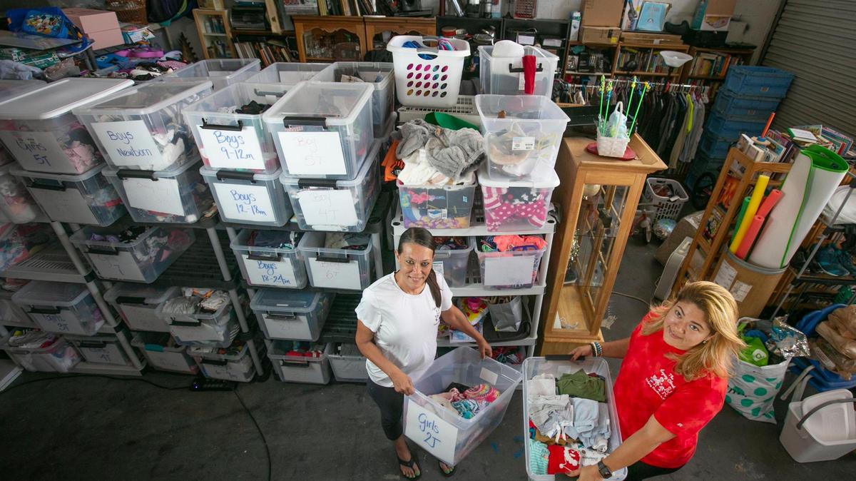 Margi Bré, left, and Jacqueline Toledo hold bins full of donated clothes inside The Legacy Closet warehouse in Cutler Bay on Oct. 7, 2021. The warehouse, which is one of three locations, is organized in order of clothing, house goods, baby needs, food and much more. People donate goods, and those in need can take them.