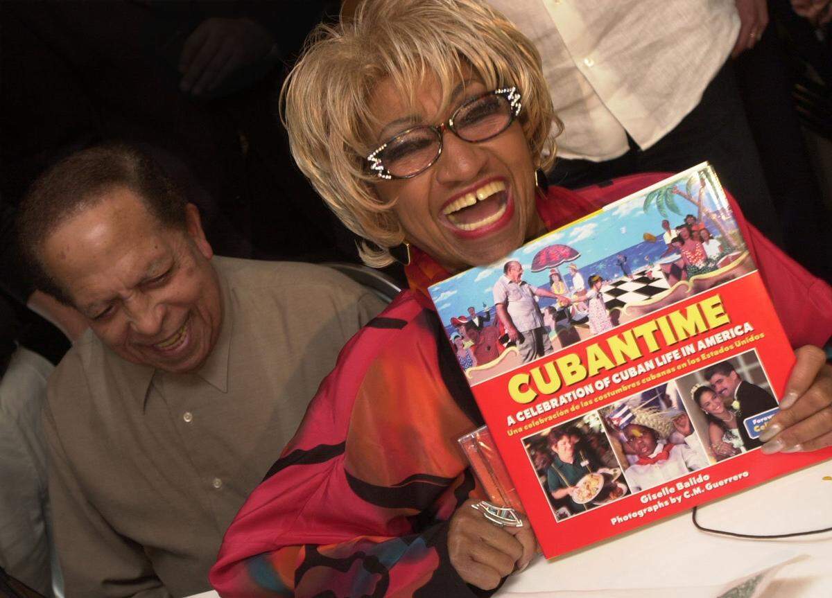 Celia Cruz holds up “Cubantime,” a book that celebrates Cuban life in America, by El Nuevo Herald photographer C.M. Guerrero and author Giselle Balido. They were all at Versailles Restaurant for a media lunch to launch the book. Cachao is on the left. Others who appeared in the book were also there.
