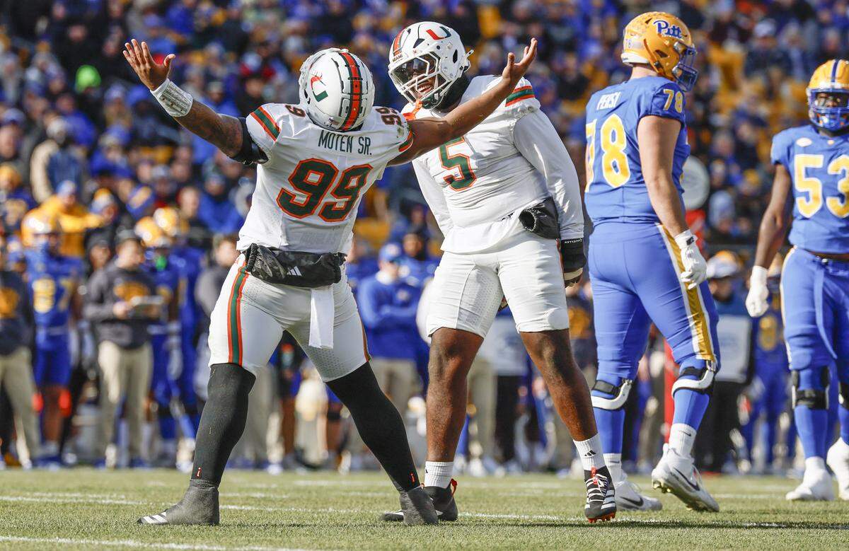 Miami Hurricanes defensive lineman Ahmad Moten (99) and defensive lineman Justin Scott (5) react after Moten sacks Pittsburgh Panthers quarterback Mason Heintschel (6) on the opening play of the game in the first half during their NCAA football game at Acrisure Stadium in Pittsburgh, PA, on Saturday, November 29, 2025.