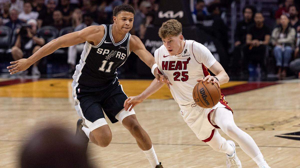 Miami Heat guard Kasparas Jakucionis (25) drives past San Antonio Spurs forward Carter Bryant (11) during the second half of an NBA preseason game at Kaseya Center on October 8, 2025, in Miami.