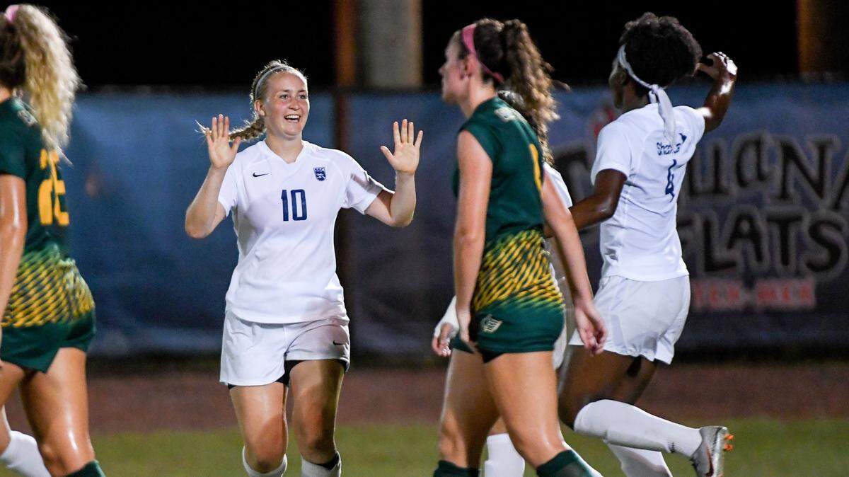 Nova Southeastern University Sharks’ Hannah Christophe (#7) and Emma Heikkila (#10) celebrate on the field.