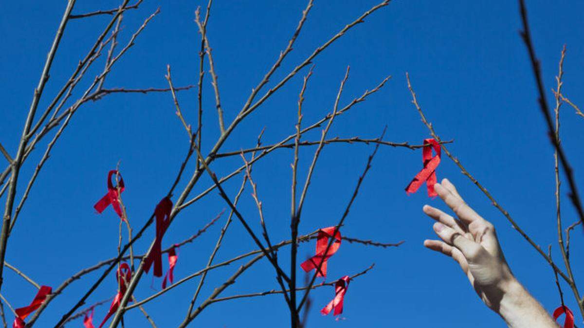 A volunteer hangs red ribbons, the universal symbol of awareness and support for those living with HIV.