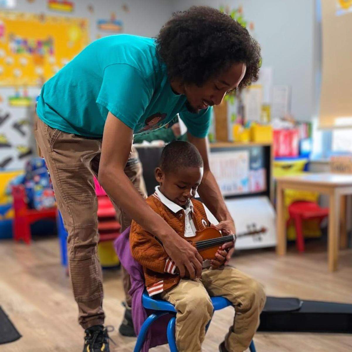 Ashani Dawkins, a Teeny Violini teaching artist, assist a student at Celebrity Kids in Miami Gardens.
