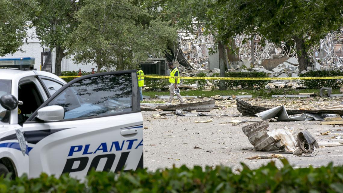 Clean-up crews walk through the parking lot at the Fountains Plaza, across the street from the explosion site in Plantation, Florida on Sunday July 7, 2019.