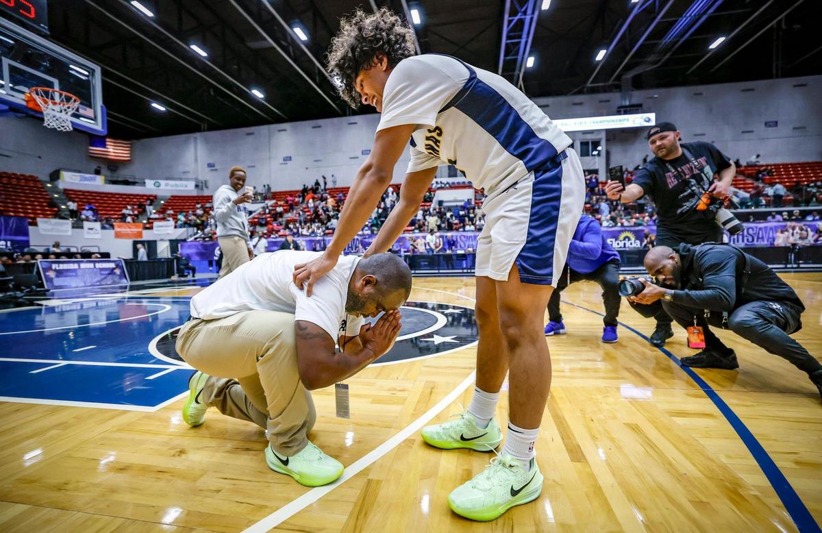 St. Thomas Aquinas Raiders head coach Julius Sandi takes a knee and gives thanks as his son DJ Sandi (2) joins him on the court as they celebrate the win over Evans in the for the FHSAA Class 6A Boys High School Basketball State Championship at the RP Funding Center in Lakeland, Florida on Saturday, March 8, 2025.