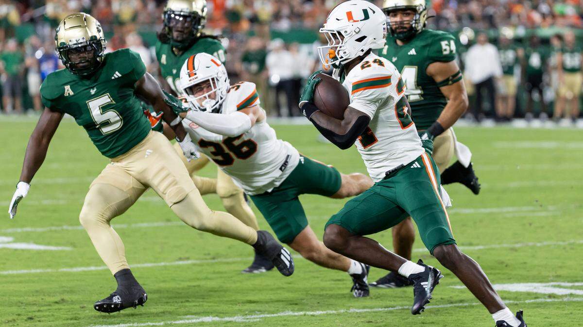 Miami Hurricanes running back Chris Johnson Jr. (24) runs with the ball as South Florida Bulls safety Caqavouis Berryhill (5) defends in the first half of their NCAA college football game at the Raymond James Stadium on Saturday, Sept. 21, 2024, in Tampa, Fla.
