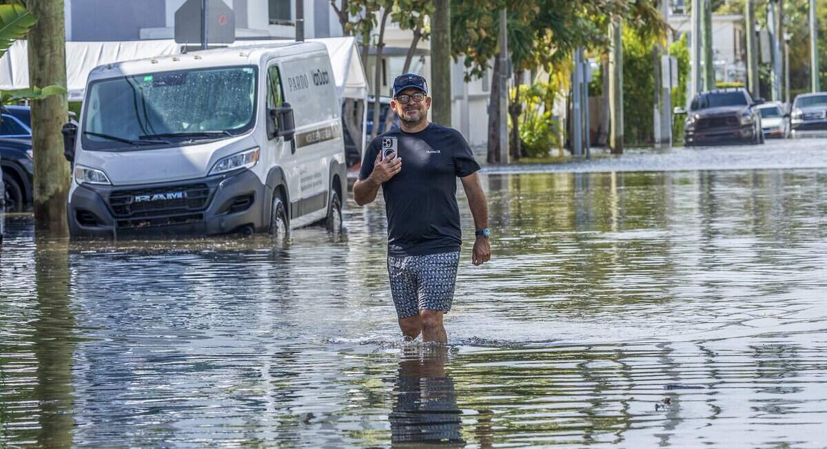 Luis Chavez Espinosa livestreams the flooding of his neighborhood on Crespi Boulevard during Tuesday’s king tide in Miami Beach.
