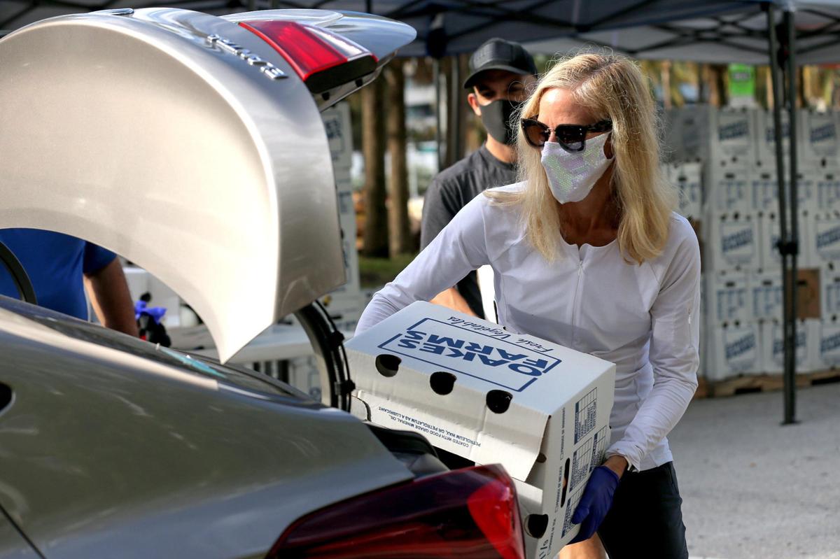 Georgi Miller, 50, loads a box with fresh vegetables into a vehicle at a food distribution event on 22nd Street and Collins Avenue in Miami Beach, Florida, on Saturday, December 5, 2020.