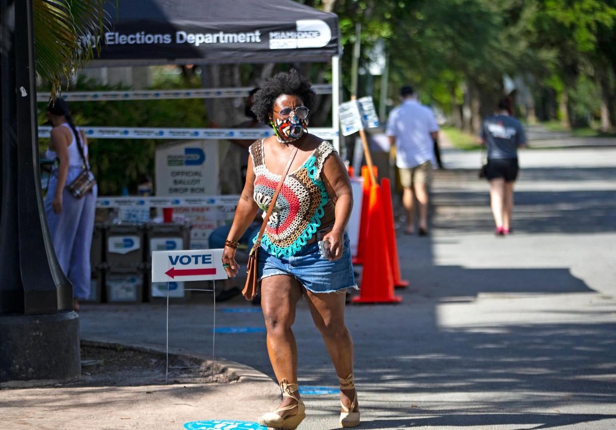 A woman walks outside the Coral Gables Library to cast her vote during the last day of early voting for the general elections on Sunday, November 1, 2020.