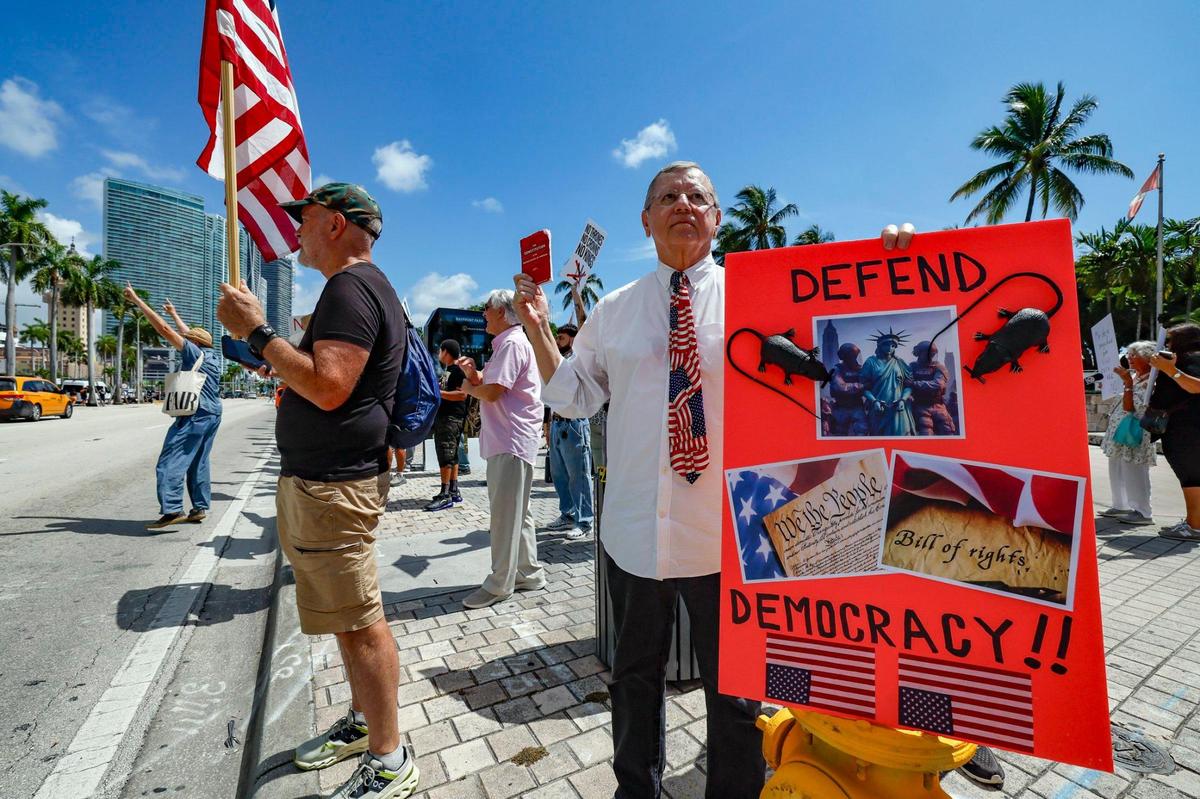 Richard Murphy, 75, holds a defend democracy sign during a ‘No Kings’ anti-Trump protest at the Torch of Friendship monument at Bayfront Park in Miami, Florida on Saturday, June 14, 2025