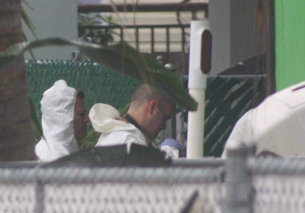 Monroe County Sheriff’s Office detectives wearing protective coveralls stand in the Cuba Road yard of a Tavernier couple found shot to death Oct. 16, 2015.