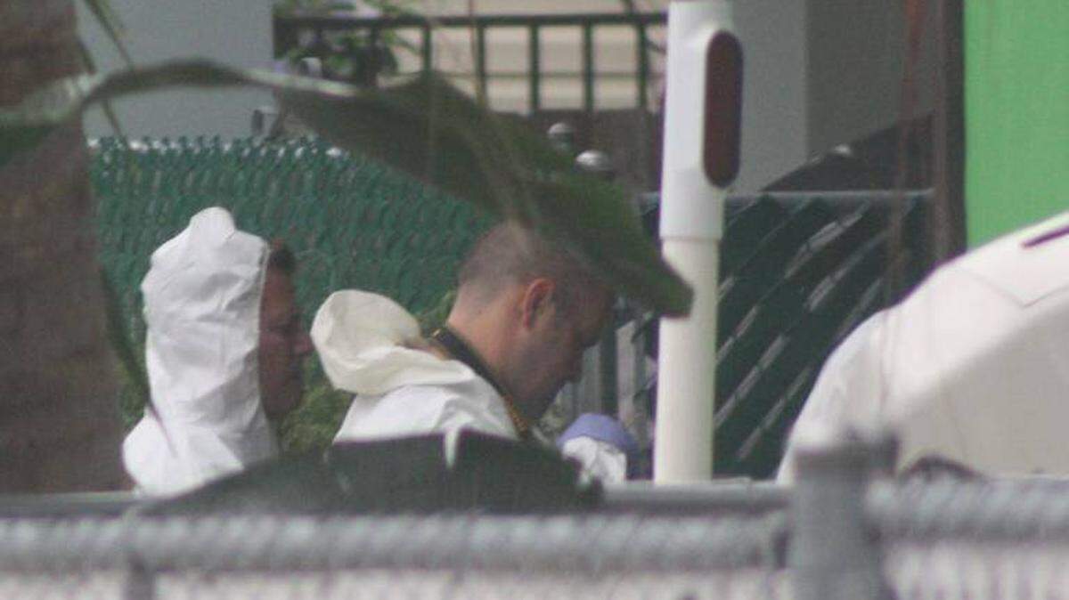 Monroe County Sheriff’s Office detectives wearing protective coveralls stand in the Cuba Road yard of a Tavernier couple found shot to death Oct. 16, 2015.