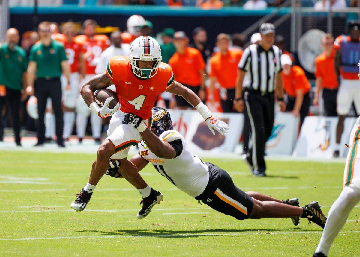 Miami Hurricanes running back Jaylan Knighton (4) runs with the football against Miami Hurricanes linebacker Wesley Bissainthe (31) during the first quarter of an NCAA non conference game at Hard Rock Stadium on Saturday, September 10, 2022 in Miami Gardens, Florida.