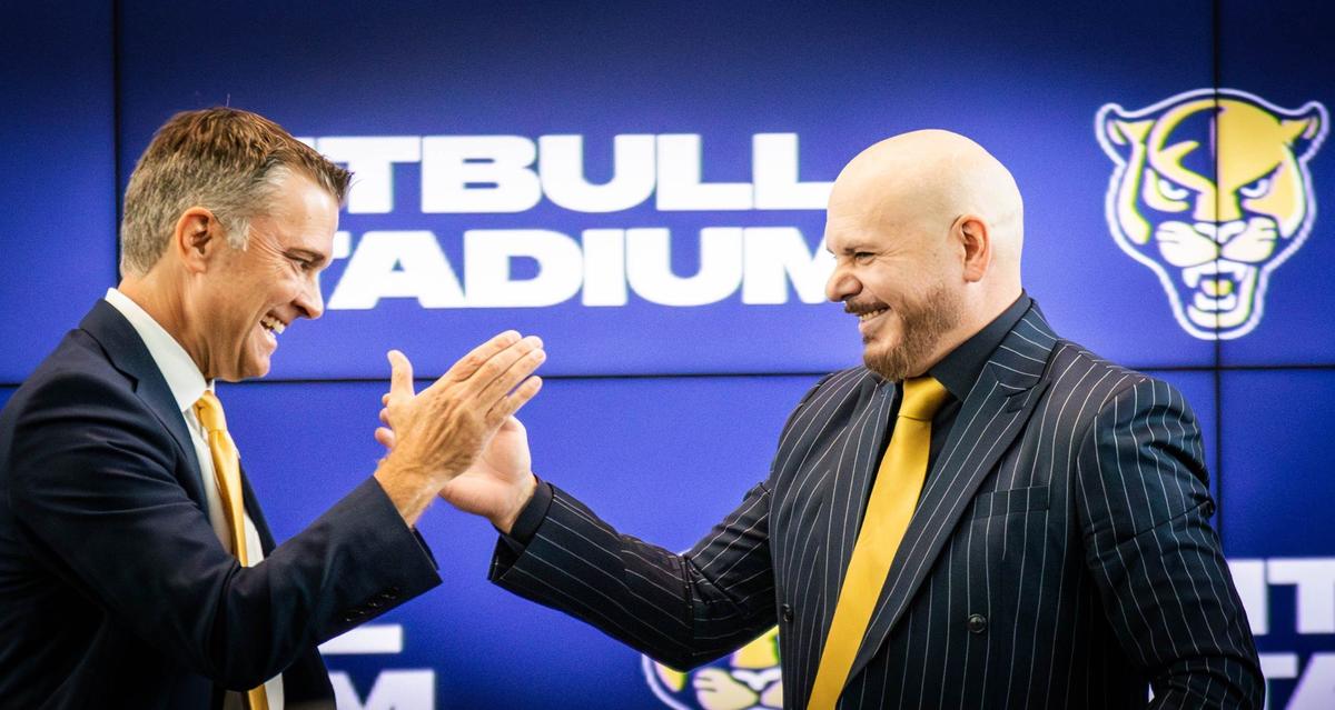 Florida International University Athletic Director Scott Carr shakes hands with Cuban-American artist Pitbull after he announces a partnership with FIU at Tamiami Hall on Tuesday, August 6, 2024 in Miami, Fla.